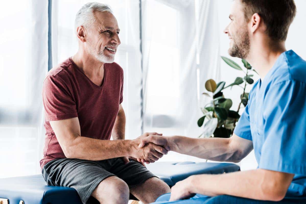 Male-patient-shaking-hands-chiropractor. Jpg Happy patient shakes hands chiropractor smiling