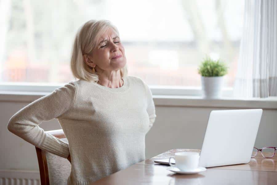 Woman-back-pain-stretching-desk Woman sitting at desk stretching desk