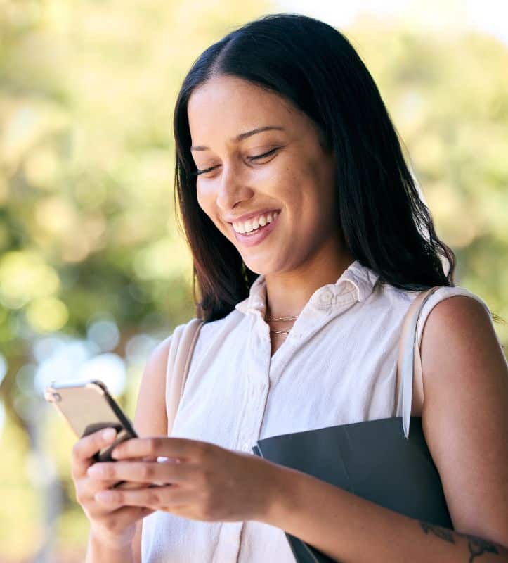 Woman-outside-phone-smiling-online Smiling woman outdoors online mobile phone