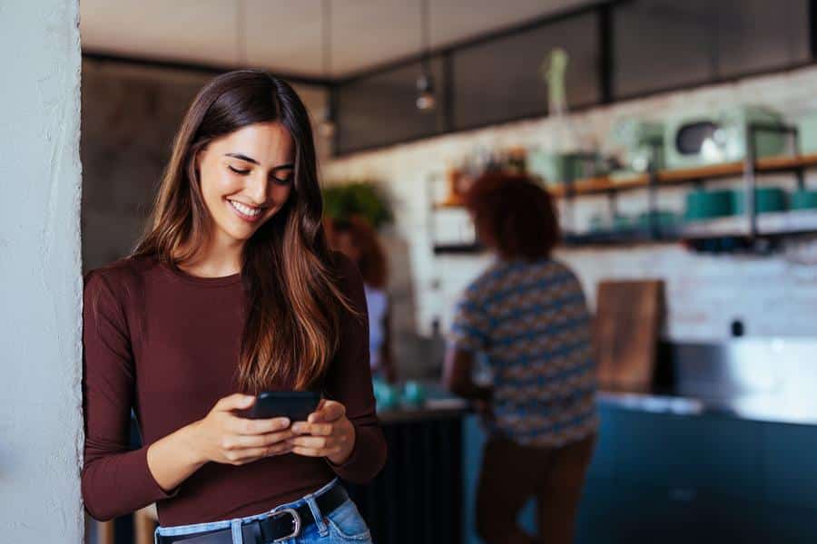 Woman-smiling-looking-phone-standing Woman looking at phone and smiling reading spinal wellness tips