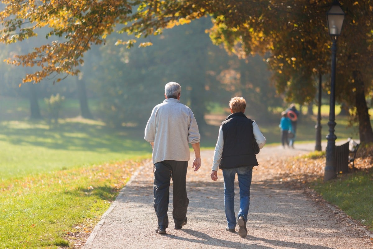 Gunderman-chiropractic-srt Older adults walking outdoors on a tree-lined path, representing improved mobility and pain relief through chiropractic care